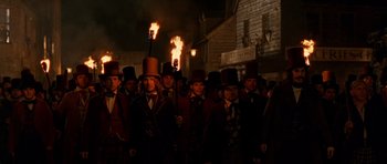 Movie still from “Gangs of New York” (2002), directed by Martin Scorsese – A group of men in top hats holding torches; Medium shot, Low angle