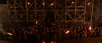 Movie still from “Gangs of New York” (2002), directed by Martin Scorsese – A large group of people holding torches in front of a building; Extreme Wide shot, High angle