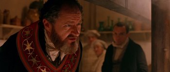 Movie still from “Gangs of New York” (2002), directed by Martin Scorsese – An old man with a beard and a mustache in front of a group of people; Close Up shot, Over the shoulder angle