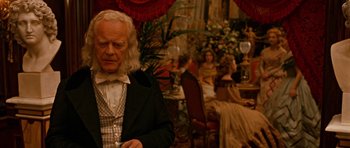 Movie still from “Gangs of New York” (2002), directed by Martin Scorsese – An old man in a suit and tie in front of a group of people; Medium shot, Over the shoulder angle