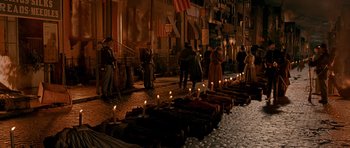 Movie still from “Gangs of New York” (2002), directed by Martin Scorsese – A group of people standing next to lit candles on the sidewalk; Wide shot, High angle