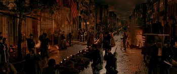 Movie still from “Gangs of New York” (2002), directed by Martin Scorsese – A group of people walking down a street with candles; Extreme Wide shot, High angle