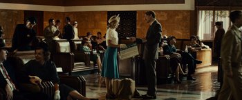 Movie still from “Gangster Squad” (2013), directed by Ruben Fleischer – A man and a woman are standing next to luggage in an airport terminal; Wide shot, Over the shoulder angle