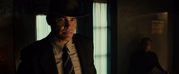 Movie still from “Gangster Squad” (2013), directed by Ruben Fleischer – A man in a suit and hat standing in front of a window; Close Up shot, Low angle