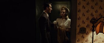 Movie still from “Gangster Squad” (2013), directed by Ruben Fleischer – A man and a woman standing next to each other in front of an elevator; Medium shot, Over the shoulder angle