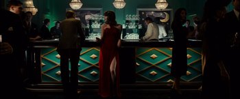 A woman in a red dress standing in front of a bar