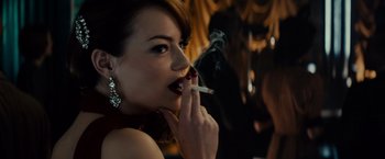 Movie still from “Gangster Squad” (2013), directed by Ruben Fleischer – A beautiful woman smoking a cigarette in a dark room; Close Up shot, Over the shoulder angle