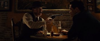 Movie still from “Gangster Squad” (2013), directed by Ruben Fleischer – Two men sitting at a table with a gun pointed at them; Medium shot, Over the shoulder angle