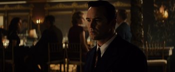 Movie still from “Gangster Squad” (2013), directed by Ruben Fleischer – A man wearing a suit and tie in a room; Medium shot, Over the shoulder angle