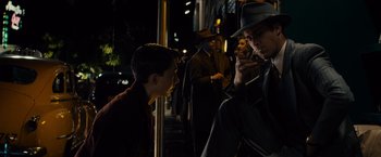 Movie still from “Gangster Squad” (2013), directed by Ruben Fleischer – A man in a hat is talking on a cell phone; Medium shot, Over the shoulder angle