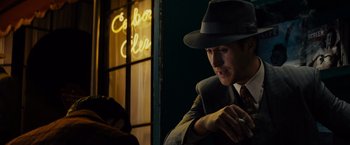 Movie still from “Gangster Squad” (2013), directed by Ruben Fleischer – A man in a suit and a hat looking at his cell phone; Close Up shot, Over the shoulder angle