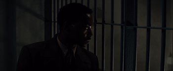 Movie still from “Gangster Squad” (2013), directed by Ruben Fleischer – A man wearing a suit and tie standing in front of a jail cell; Close Up shot, High angle