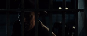 Movie still from “Gangster Squad” (2013), directed by Ruben Fleischer – A man with a hat is behind bars in the dark; Close Up shot, Low angle