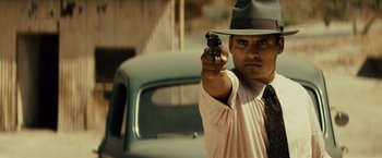 Movie still from “Gangster Squad” (2013), directed by Ruben Fleischer – A man holding a gun while standing next to a car; Close Up shot, Low angle