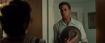 Movie still from “Gangster Squad” (2013), directed by Ruben Fleischer – A man in white shirt holding a hat in front of a mirror; Close Up shot, Over the shoulder angle