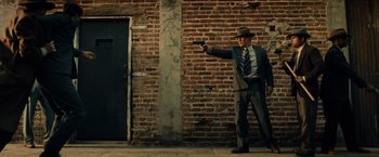 Movie still from “Gangster Squad” (2013), directed by Ruben Fleischer – A man in a suit and tie holding a gun; Wide shot, Low angle