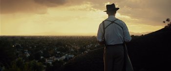 A man standing on top of a hill looking at a city
