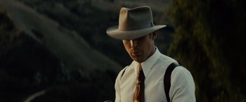 Movie still from “Gangster Squad” (2013), directed by Ruben Fleischer – A man wearing a hat and a tie standing in front of a mountain range; Close Up shot, Low angle