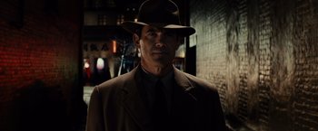 Movie still from “Gangster Squad” (2013), directed by Ruben Fleischer – A man wearing a suit and a hat in the dark; Close Up shot, Low angle