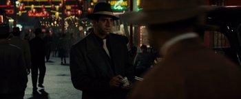 Movie still from “Gangster Squad” (2013), directed by Ruben Fleischer – A man in a suit and hat holding a cigarette; Medium shot, Over the shoulder angle