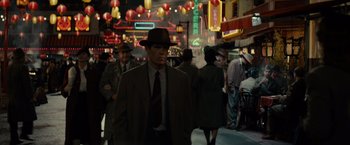 Movie still from “Gangster Squad” (2013), directed by Ruben Fleischer – A man in a suit and a hat walking down a street; Wide shot, Over the shoulder angle