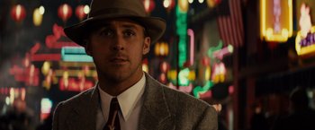 Movie still from “Gangster Squad” (2013), directed by Ruben Fleischer – A man wearing a suit and a hat in front of neon lights; Close Up shot, Over the shoulder angle