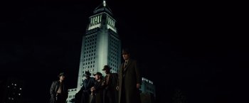 Movie still from “Gangster Squad” (2013), directed by Ruben Fleischer – A group of men standing next to each other in front of a building; Extreme Wide shot, Low angle