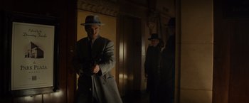Movie still from “Gangster Squad” (2013), directed by Ruben Fleischer – A man in a hat holding a gun in a room; Medium shot, Low angle