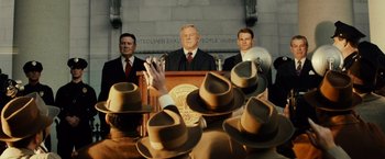 Movie still from “Gangster Squad” (2013), directed by Ruben Fleischer – A group of men standing in front of a podium; Medium shot, Over the shoulder angle