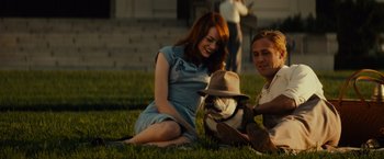 Movie still from “Gangster Squad” (2013), directed by Ruben Fleischer – A man and a woman sitting in the grass next to a dog; Medium shot, Over the shoulder angle