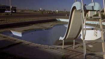 Movie still from “Gas Food Lodging” (1992), directed by Allison Anders – An empty swimming pool with a slide in the middle; Extreme Wide shot, High angle