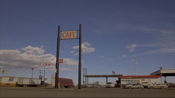 Movie still from “Gas Food Lodging” (1992), directed by Allison Anders – An empty parking lot with a cafe sign on it; Extreme Wide shot, Low angle