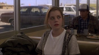 Movie still from “Gas Food Lodging” (1992), directed by Allison Anders – A woman sitting at a table in front of a window; Medium shot, Over the shoulder angle