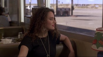 Movie still from “Gas Food Lodging” (1992), directed by Allison Anders – A woman sitting on a couch looking out a window; Medium shot, Over the shoulder angle