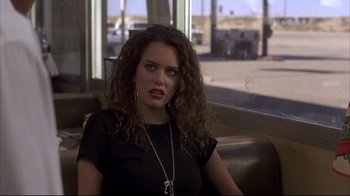 Movie still from “Gas Food Lodging” (1992), directed by Allison Anders – A woman sitting in a booth looking at the camera; Close Up shot, Over the shoulder angle