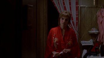 Movie still from “Gas Food Lodging” (1992), directed by Allison Anders – A woman in a red robe is holding a remote control; Medium shot, Over the shoulder angle