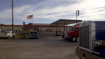 Movie still from “Gas Food Lodging” (1992), directed by Allison Anders – An american flag flies in front of a gas station; Extreme Wide shot, Low angle