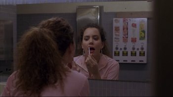 Movie still from “Gas Food Lodging” (1992), directed by Allison Anders – A woman in a pink shirt putting lipstick in a bathroom mirror; Close Up shot, Over the shoulder angle