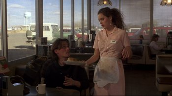 Movie still from “Gas Food Lodging” (1992), directed by Allison Anders – A woman in a pink shirt is serving a man in a black shirt in a restaurant; Medium shot, Over the shoulder angle