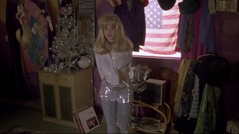 Movie still from “Gas Food Lodging” (1992), directed by Allison Anders – A woman standing in front of an american flag window; Medium shot, High angle