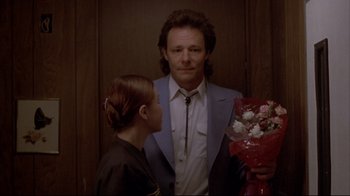 Movie still from “Gas Food Lodging” (1992), directed by Allison Anders – A man and a woman standing next to each other holding flowers; Medium shot, Over the shoulder angle