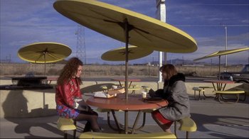 Movie still from “Gas Food Lodging” (1992), directed by Allison Anders – Two women are sitting at a table under an umbrella; Wide shot, High angle