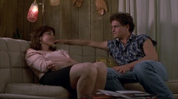 Movie still from “Gas Food Lodging” (1992), directed by Allison Anders – A man and a woman sitting on a couch arm in arm; Medium shot, Low angle