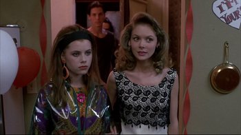 Movie still from “Gas Food Lodging” (1992), directed by Allison Anders – Two young women standing next to each other in front of a doorway; Medium shot, Over the shoulder angle