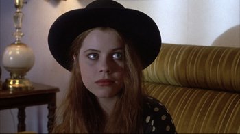 Movie still from “Gas Food Lodging” (1992), directed by Allison Anders – A woman wearing a black hat sitting on a yellow couch; Close Up shot, High angle