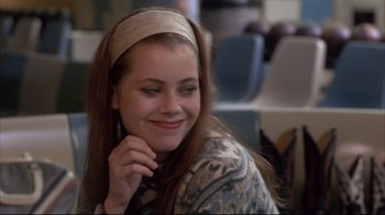 Movie still from “Gas Food Lodging” (1992), directed by Allison Anders – A woman with long brown hair wearing a headband; Close Up shot, Over the shoulder angle