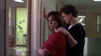 Movie still from “Gas Food Lodging” (1992), directed by Allison Anders – A man and a woman standing next to each other in front of a window; Medium shot, Low angle