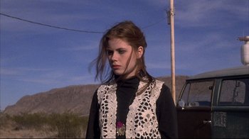 Movie still from “Gas Food Lodging” (1992), directed by Allison Anders – A woman in a black shirt and a white vest standing in front of a truck; Medium shot, Low angle