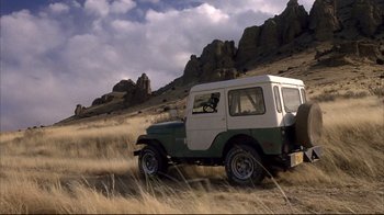 Movie still from “Gas Food Lodging” (1992), directed by Allison Anders – A jeep is driving through a grassy field; Wide shot, Low angle
