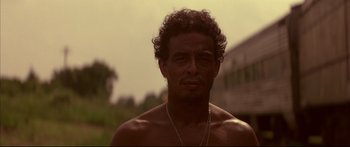 Movie still from “George Washington” (2000), directed by David Gordon Green – A shirtless man with curly brown hair wearing a necklace; Close Up shot, Low angle